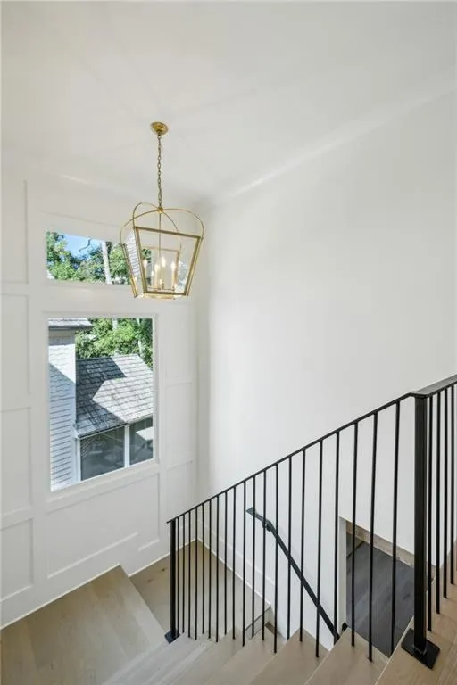 Stairway featuring an inviting chandelier and wood-type flooring