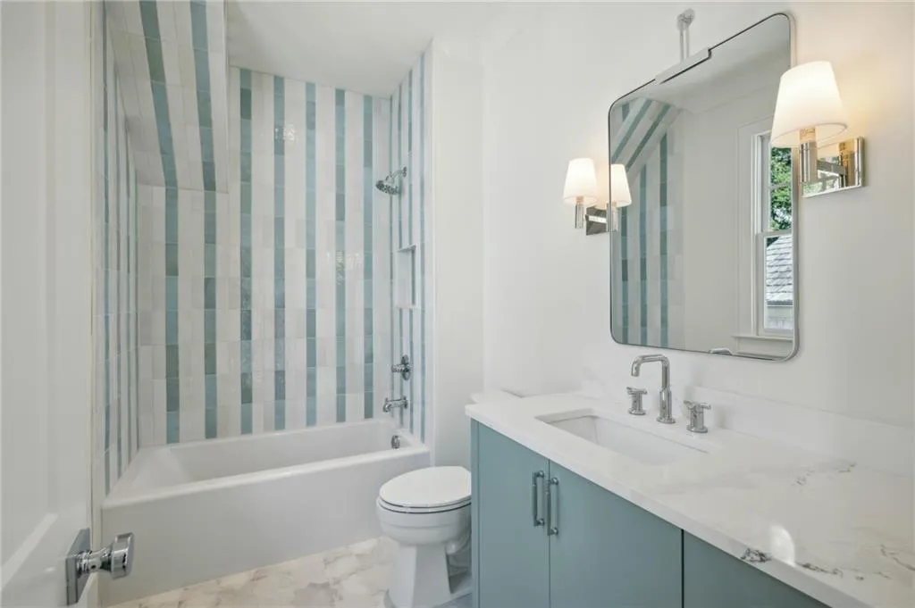 Full bathroom featuring vanity, tiled shower / bath combo, and toilet