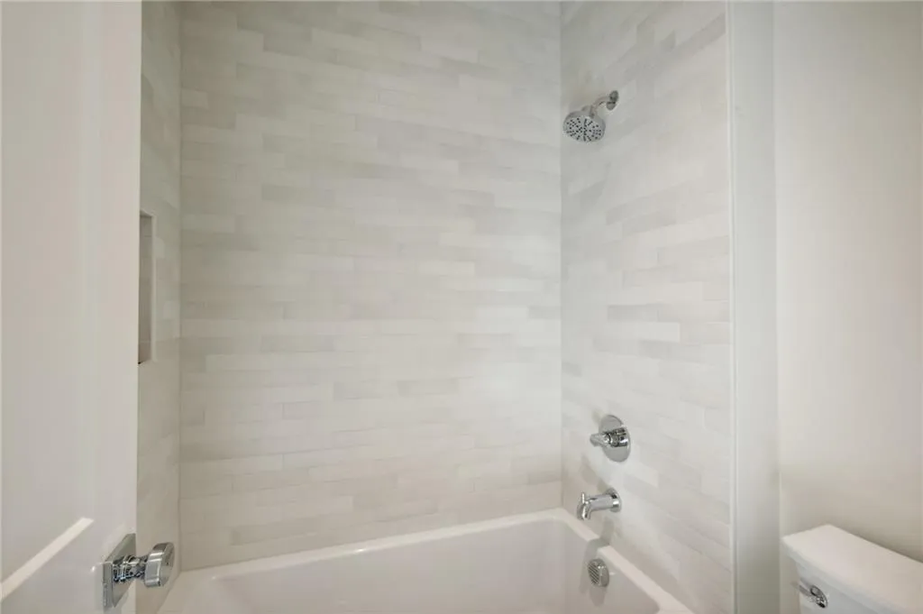 Bathroom with tiled shower / bath combo and toilet