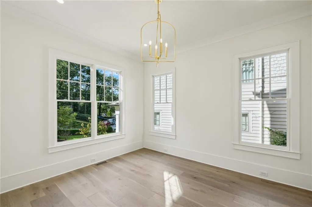 Unfurnished dining area featuring hardwood / wood-style flooring, ornamental molding, and an inviting chandelier
