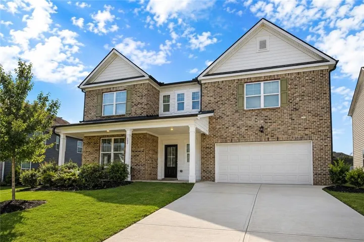 Traditional two-story residence with brick and siding exterior, a covered front porch, an attached two-car garage, and a concrete driveway