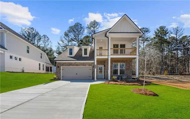 Modern farmhouse exterior with brick and siding, featuring a two-story covered porch with railings, a two-car garage, and a concrete driveway