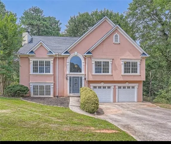 Bi-level home featuring stucco siding, a front yard, concrete driveway, and an attached garage