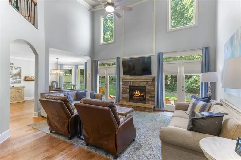 Living room with a stone fireplace, light hardwood / wood-style floors, and a healthy amount of sunlight