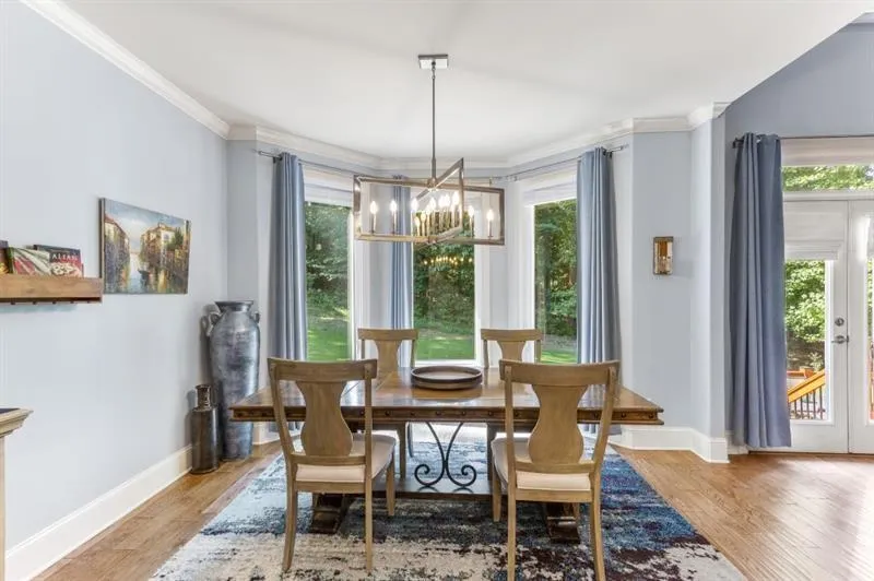 Dining area with french doors, ornamental molding, hardwood / wood-style floors, and a notable chandelier