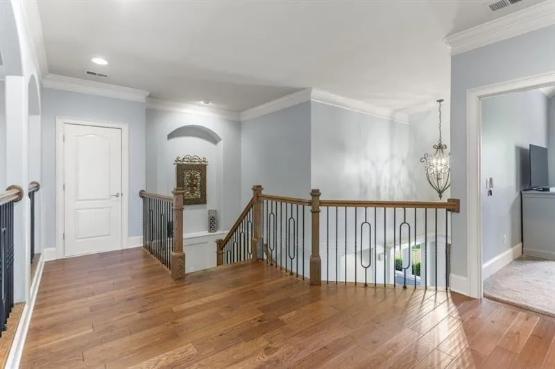 Hall with ornamental molding, wood-type flooring, and a chandelier