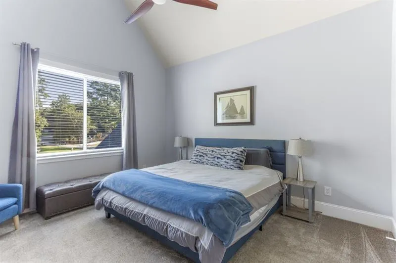 Carpeted bedroom with high vaulted ceiling and ceiling fan