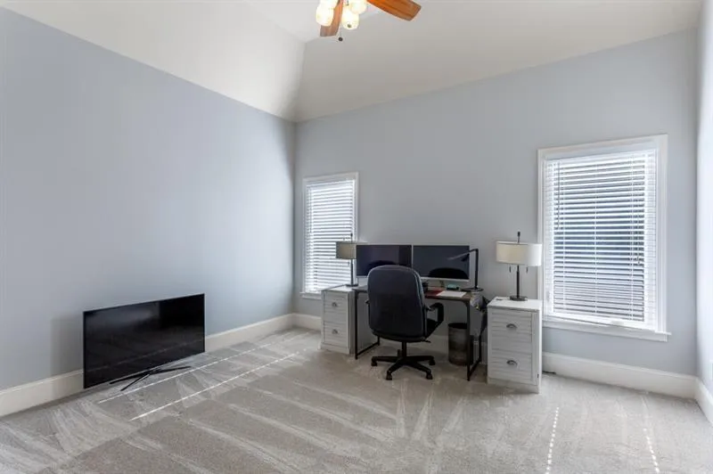 Carpeted office with ceiling fan and lofted ceiling