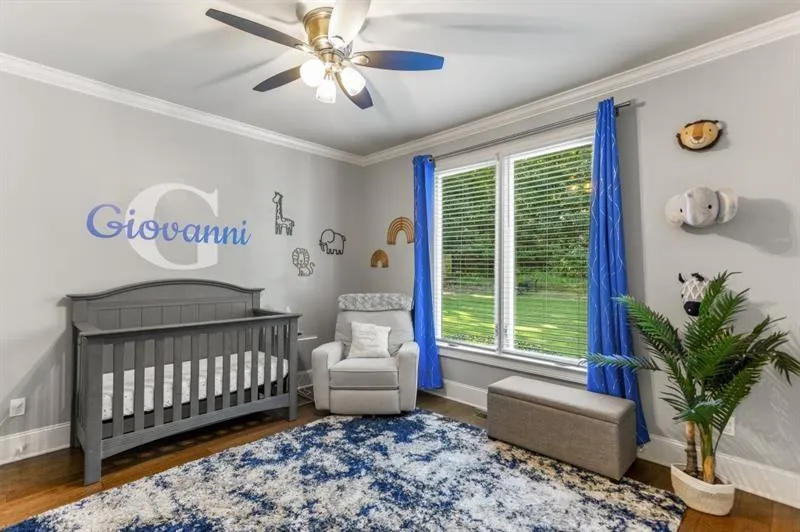 Bedroom featuring ceiling fan, ornamental molding, dark hardwood / wood-style floors, and a crib