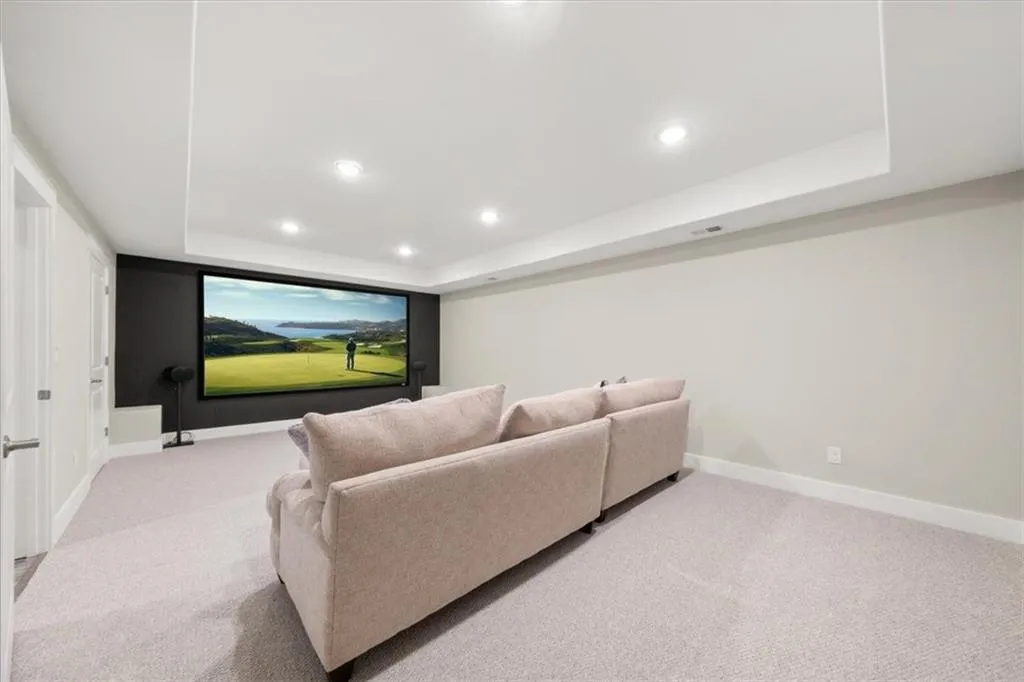 Carpeted home theater room with a tray ceiling