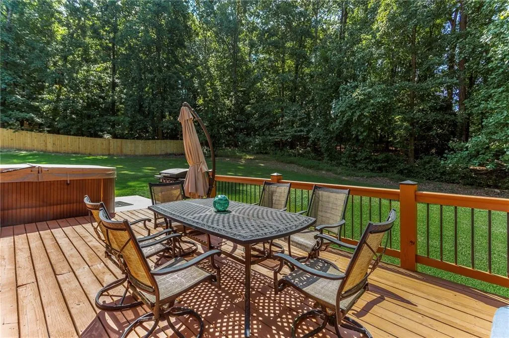 Wooden terrace with a hot tub and a yard