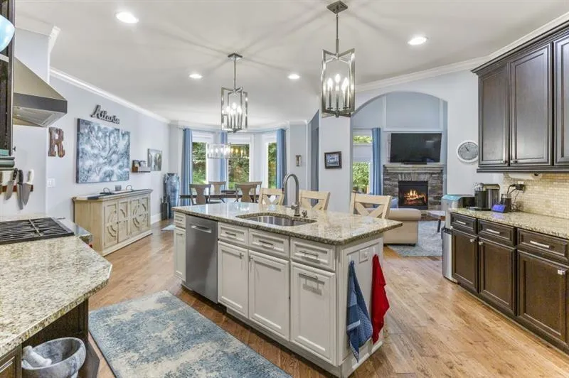 Kitchen featuring sink, stainless steel appliances, dark brown cabinetry, an island with sink, and decorative light fixtures