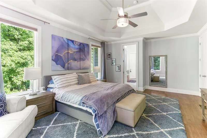 Bedroom with a tray ceiling, dark hardwood / wood-style floors, and multiple windows