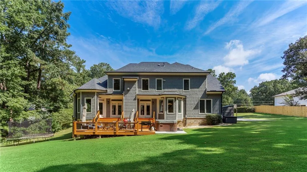 Back of house featuring a hot tub, a deck, and a lawn