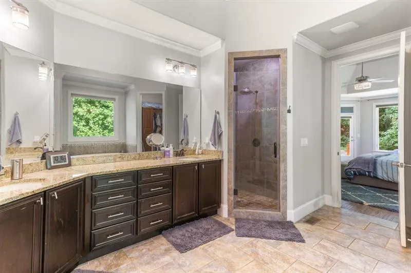 Bathroom with vanity, a shower with shower door, ornamental molding, and a healthy amount of sunlight