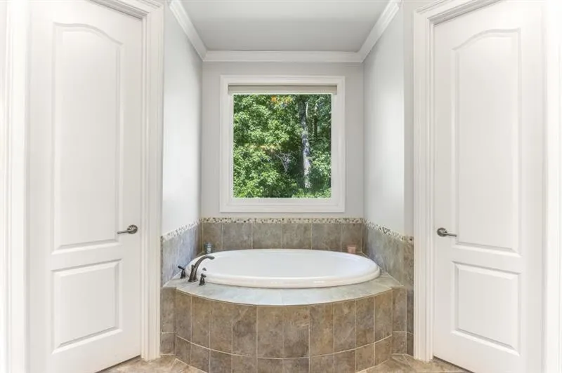 Bathroom with tiled tub and crown molding