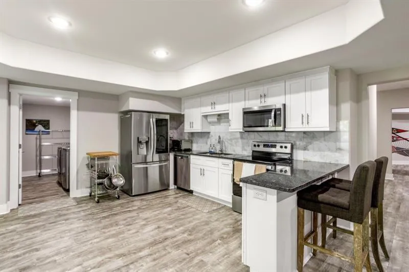Kitchen with a breakfast bar area, white cabinetry, stainless steel appliances, light hardwood / wood-style floors, and kitchen peninsula