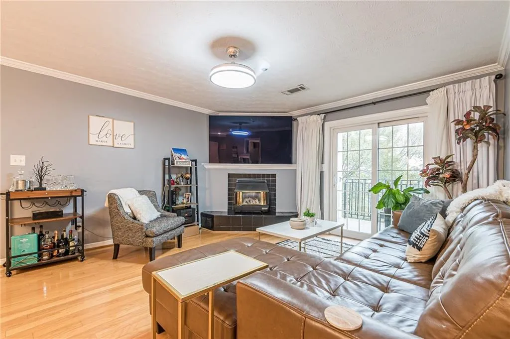 Living area with crown molding, wood finished floors, a tiled fireplace, and a textured ceiling