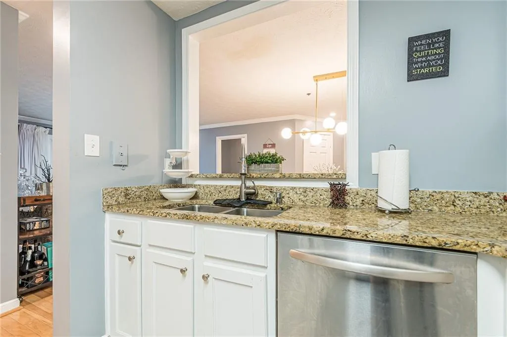 Kitchen featuring dishwasher, white cabinetry, light stone countertops, crown molding, and light wood-type flooring