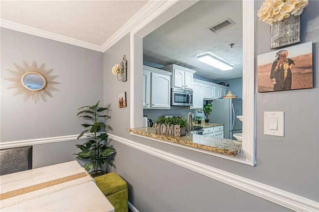 Kitchen featuring appliances with stainless steel finishes, a textured ceiling, crown molding, and light stone countertops