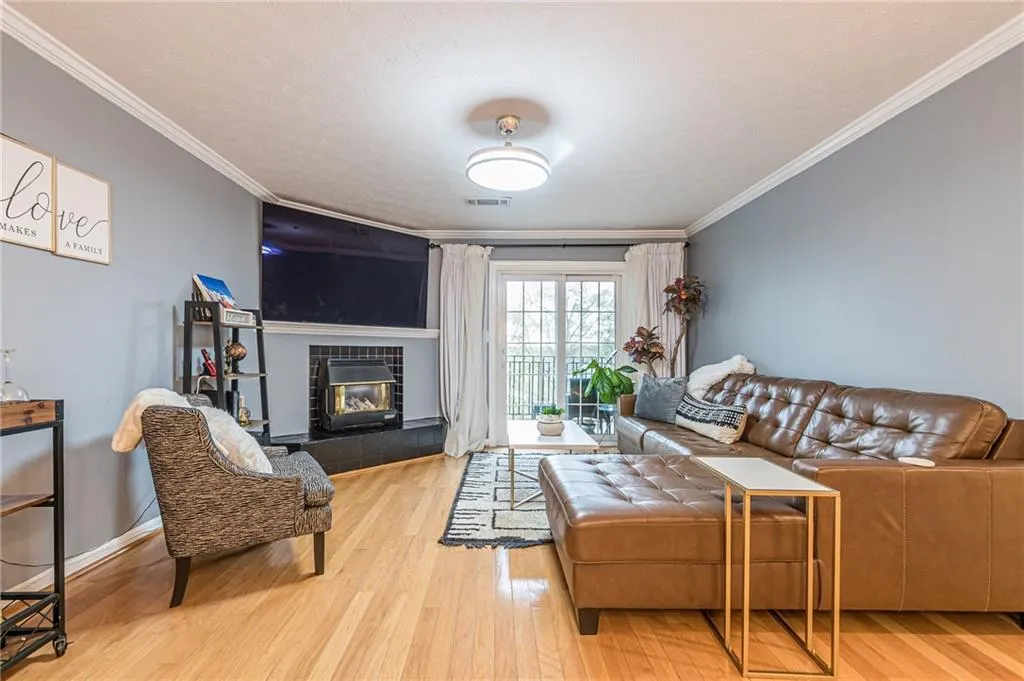 Living room featuring wood finished floors, a tile fireplace, crown molding, and a textured ceiling