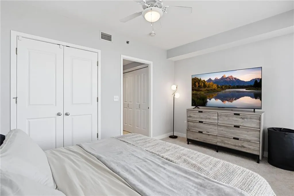 Ceiling fan with integrated lighting, recessed architectural detailing, white paneled doors, and carpeted flooring