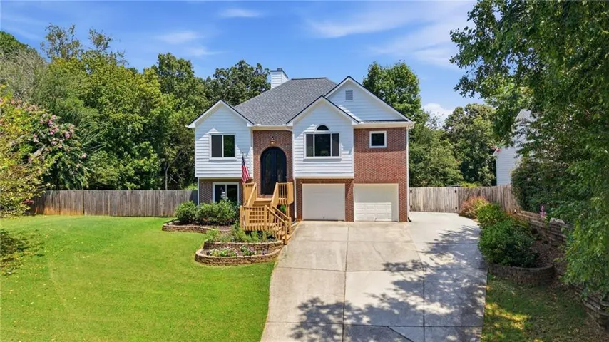 Two-story home featuring a brick and siding exterior, arched front entry, double garage, and a concrete driveway