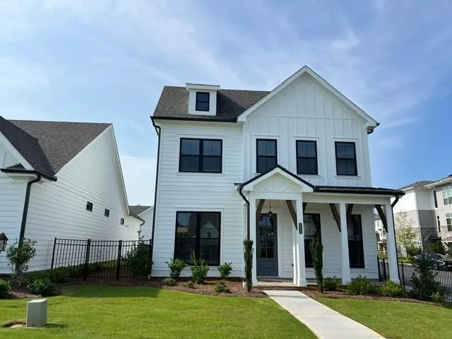 Modern farmhouse exterior featuring white siding, black-framed windows, a covered entry with timber accents, and a dormer window