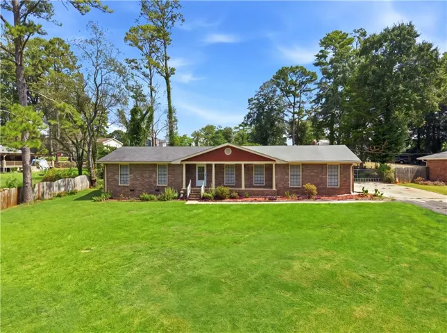 Brick exterior with a covered entry, white columns, and a front yard with mature landscaping