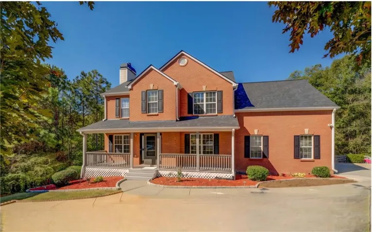 View of front of home with covered porch, a chimney, and brick siding