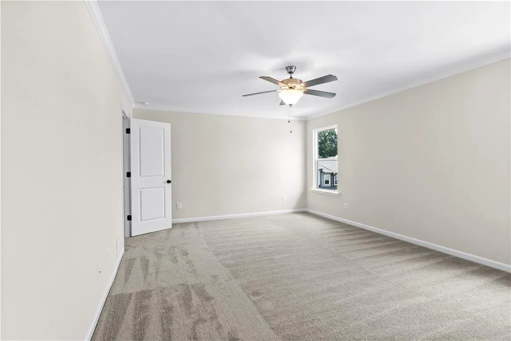 Empty room featuring crown molding, light carpet, and ceiling fan