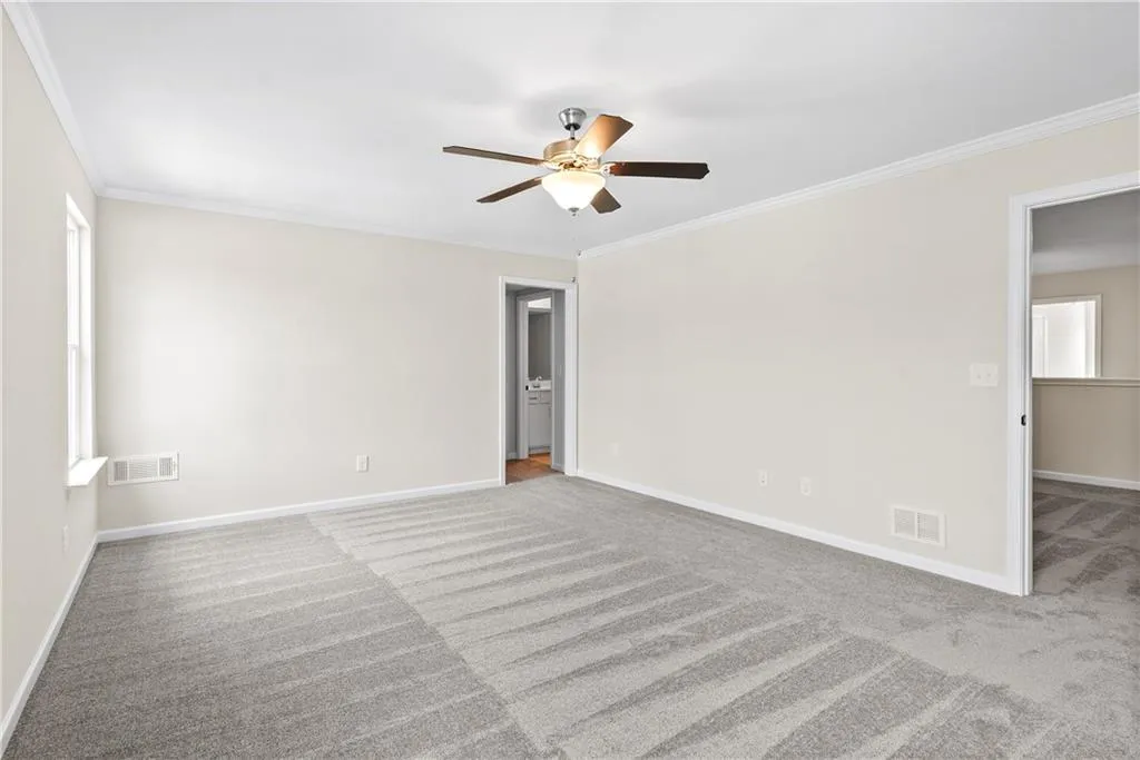 Empty room with light carpet, crown molding, and ceiling fan