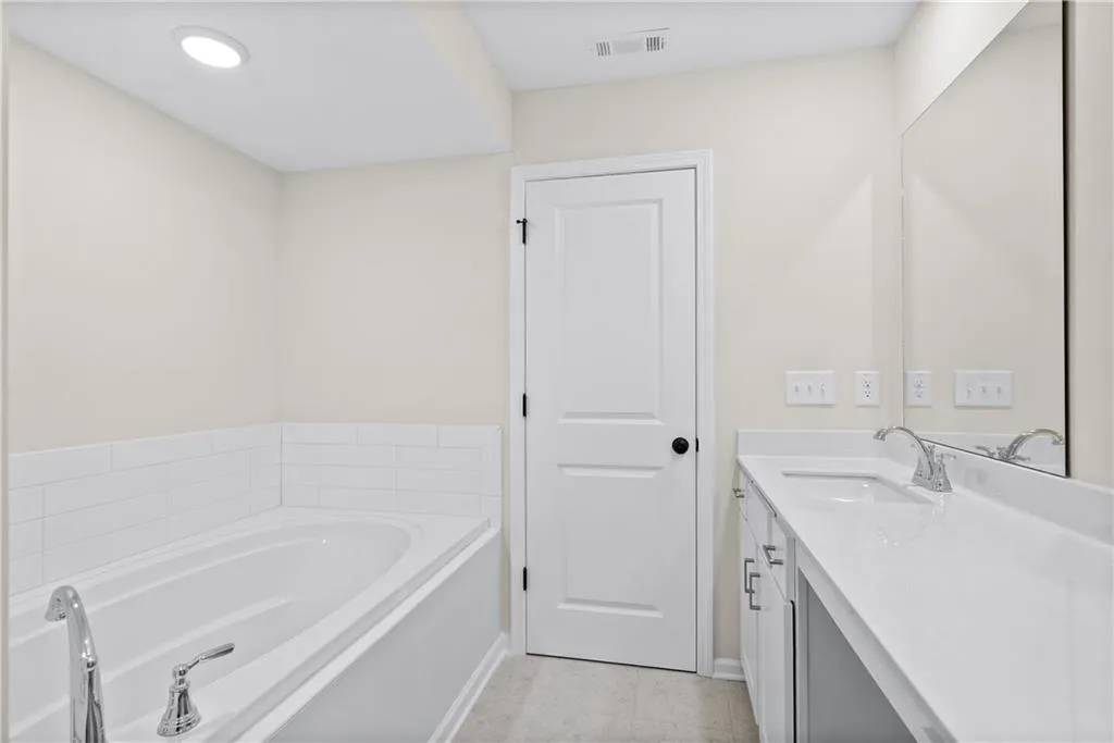 Bathroom with vanity, a garden tub, light tile patterned flooring, and recessed lighting