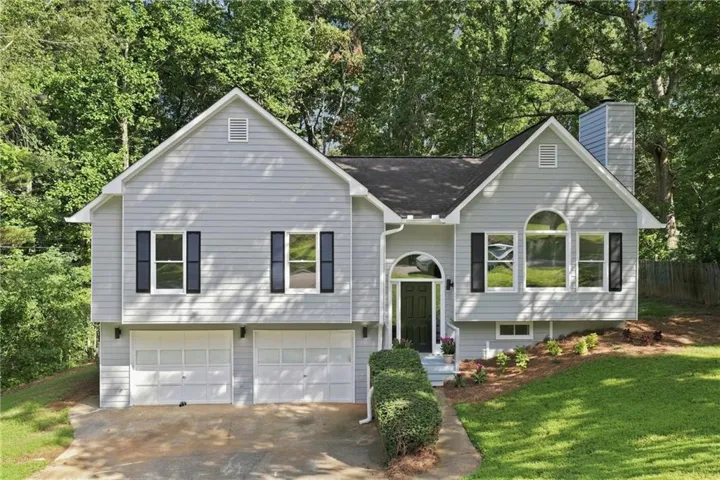 Light gray siding exterior with a black front door, arched entryway, and a two-car garage