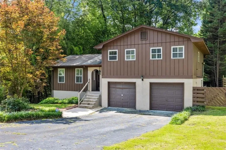 Brown board-and-batten exterior with white trim windows and a two-car garage