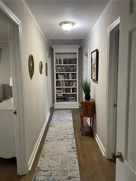 Hall featuring built in features, crown molding, and dark wood finished floors