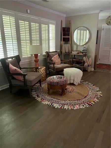 Sitting room with ornamental molding and dark wood-type flooring