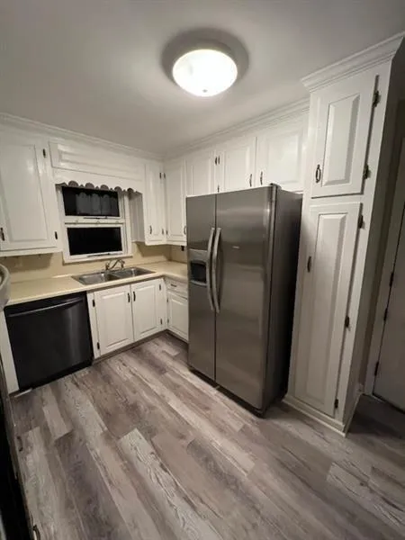 Kitchen with white cabinetry, stainless steel refrigerator with ice dispenser, light countertops, and black dishwasher