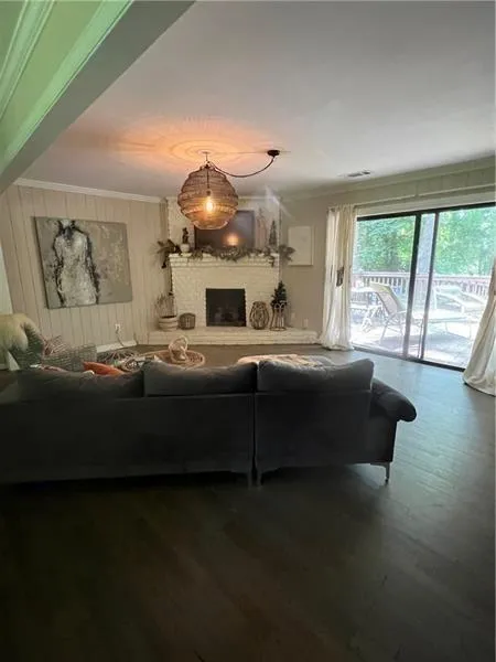 Living area featuring ornamental molding, dark wood-style flooring, and a brick fireplace