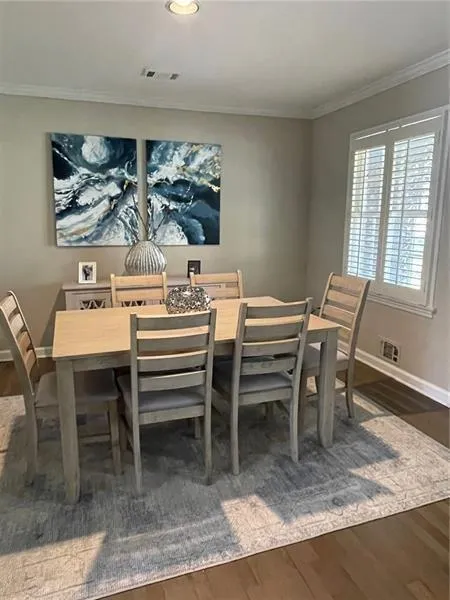 Dining area with dark wood-style flooring, ornamental molding, and recessed lighting