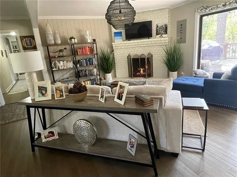 Living area with ornamental molding, a brick fireplace, and wood-type flooring