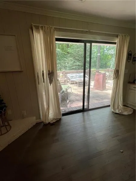 Doorway featuring crown molding, plenty of natural light, wood finished floors, and wood walls