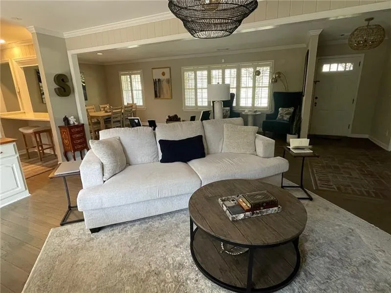 Living area with a chandelier, ornamental molding, healthy amount of natural light, and wood finished floors