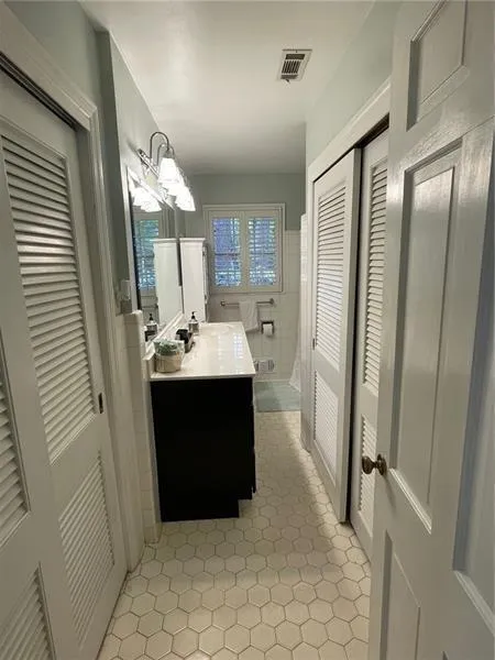 Full bathroom featuring vanity, a closet, tile walls, and light tile patterned floors