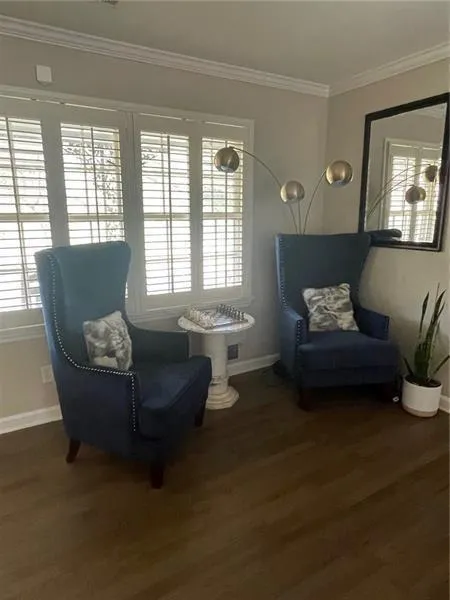 Sitting room with ornamental molding and dark wood-style flooring