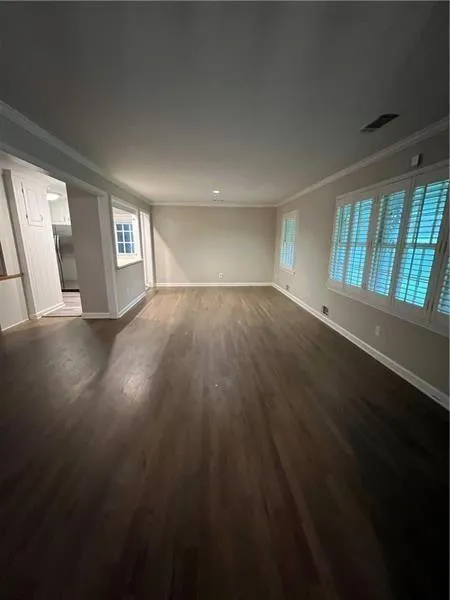 Unfurnished living room with crown molding and dark wood-type flooring