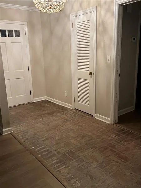 Unfurnished dining area featuring brick floors and a chandelier