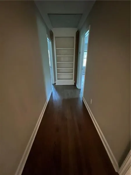 Hall featuring built in shelves, attic access, and dark wood finished floors