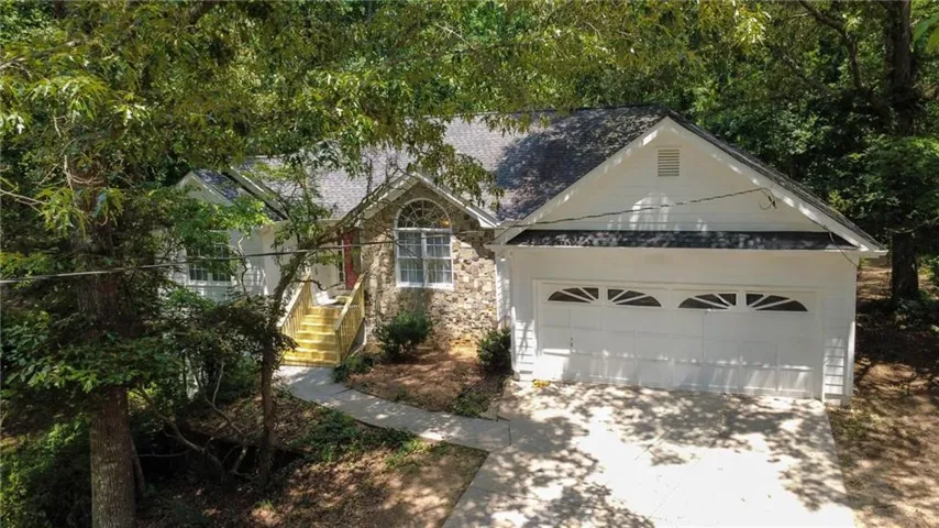 Architectural exterior featuring a stone facade, a two-car garage with decorative window inserts, and an arched window