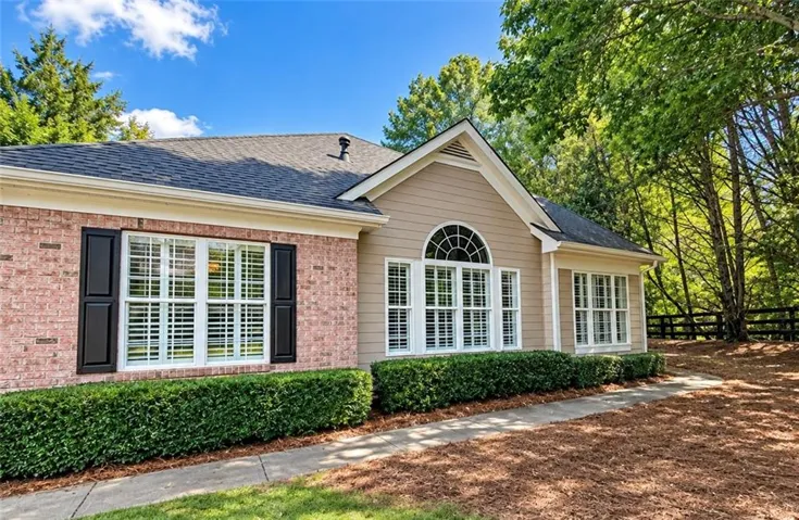 Brick and siding exterior with dark shutters, arched window, and white window frames